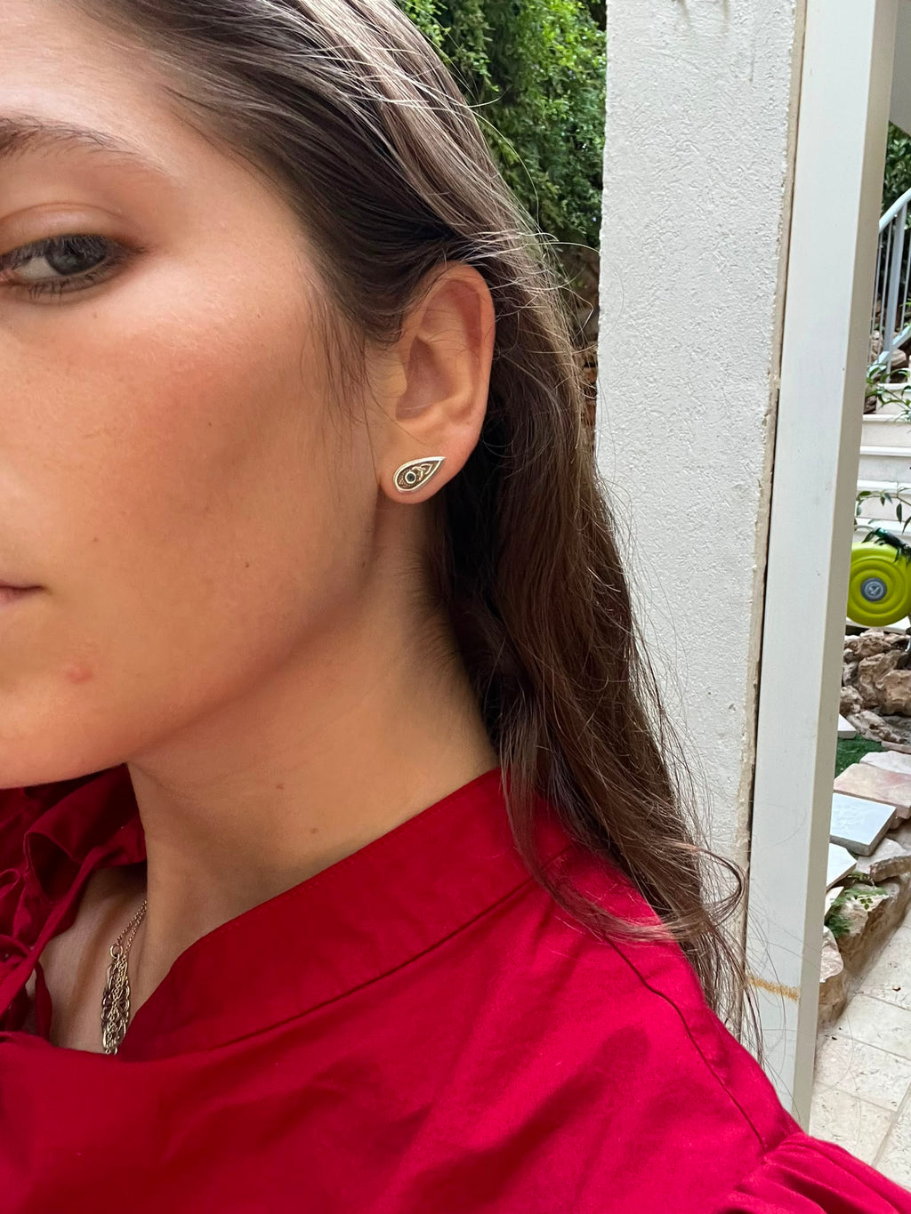 side profile of a woman wearing a small teardrop-shaped silver earring set with a blue gemstone