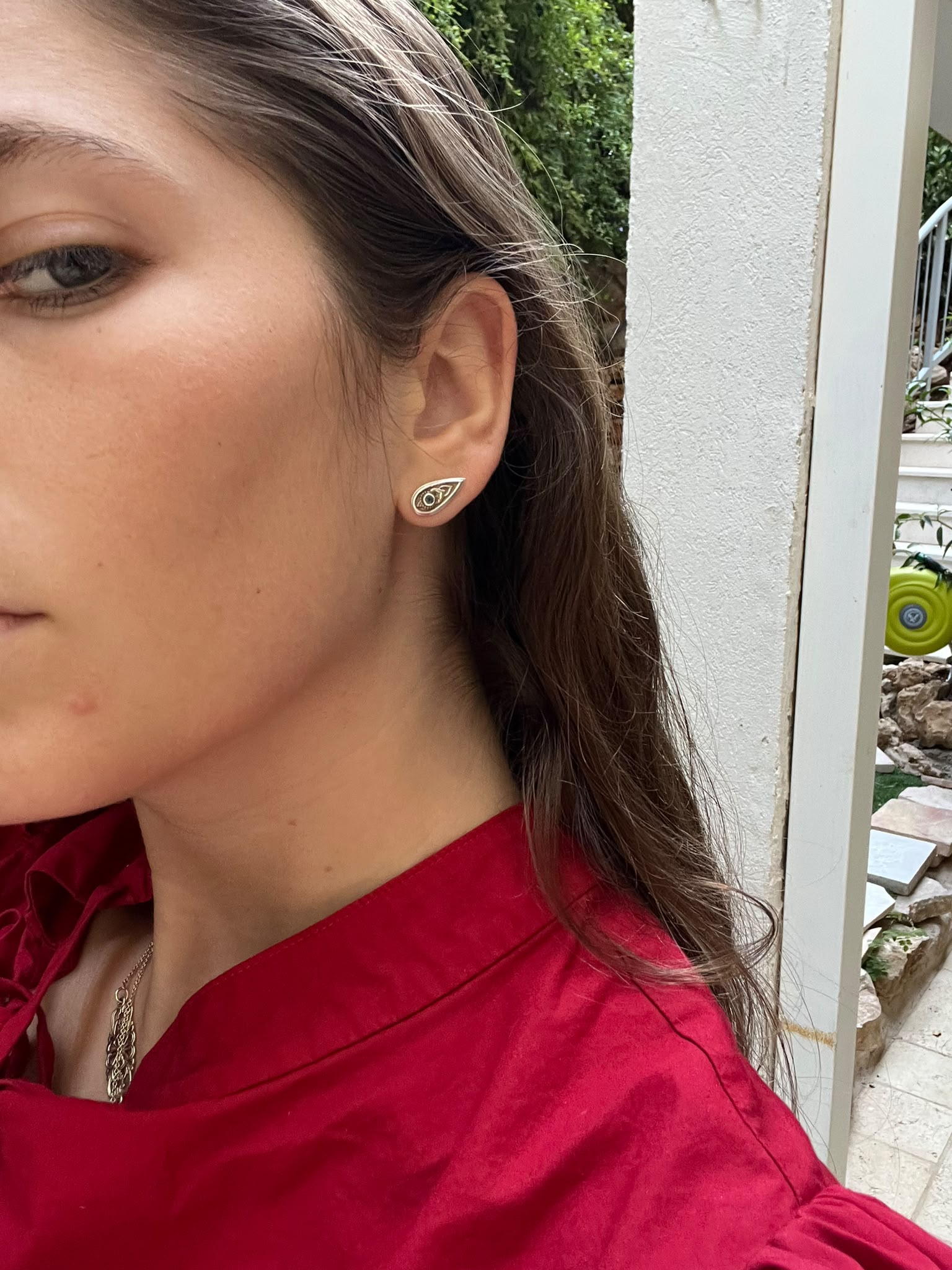 side profile of a woman wearing a small teardrop-shaped silver earring set with a blue gemstone